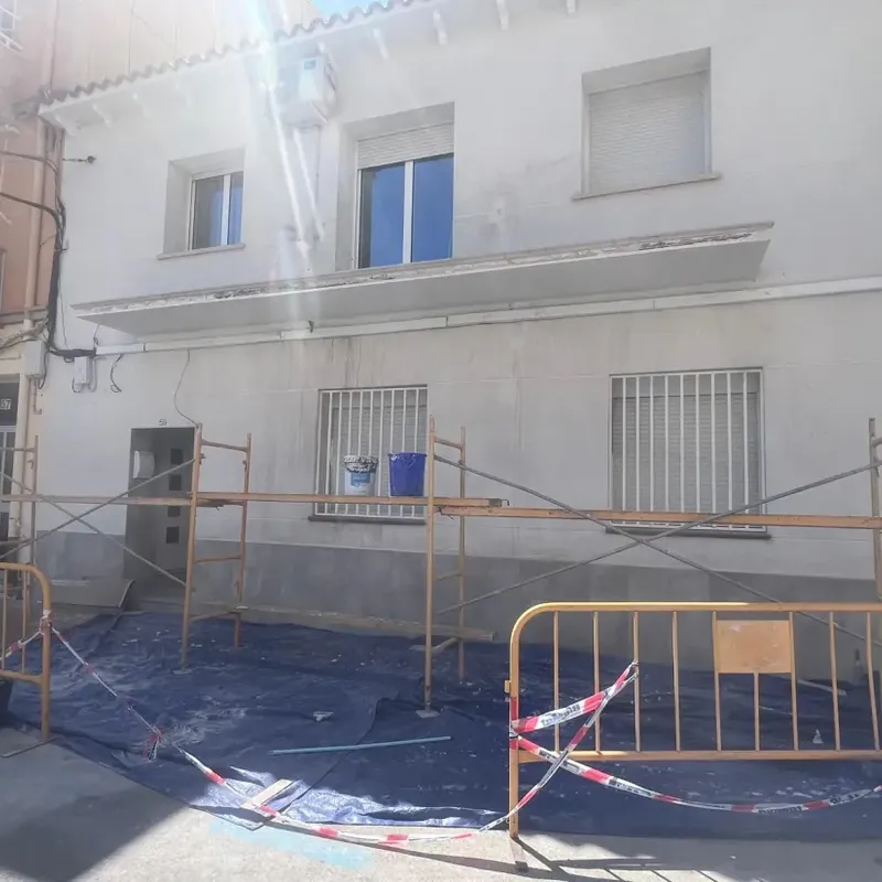 Fachada de edificio con la pintura desgastada y desconchados antes de rehabilitarla