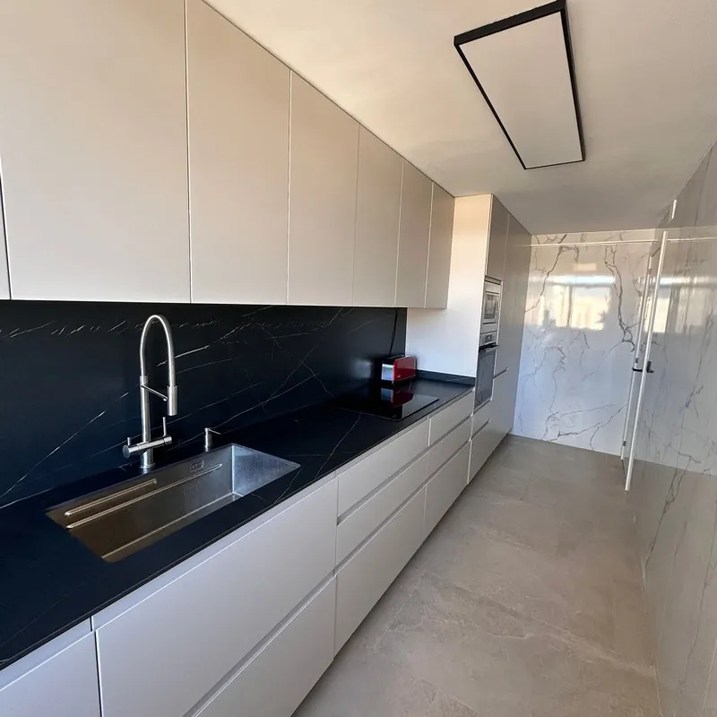 Cocina greige con encimera y frente negros, fregadero bajo encimera y grifo abatible